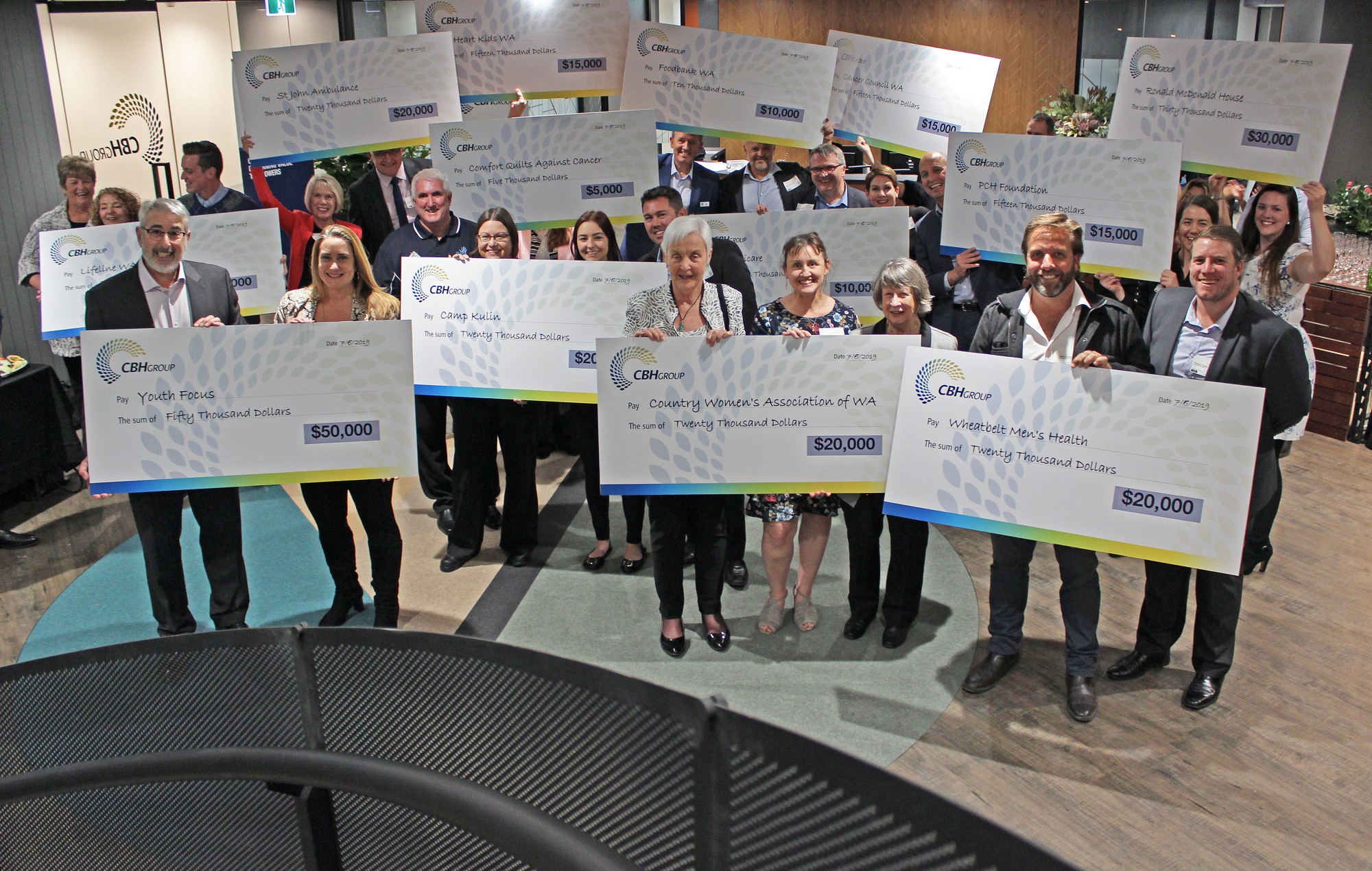 Groups of HMMS donation recipients holding giant cheques smiling