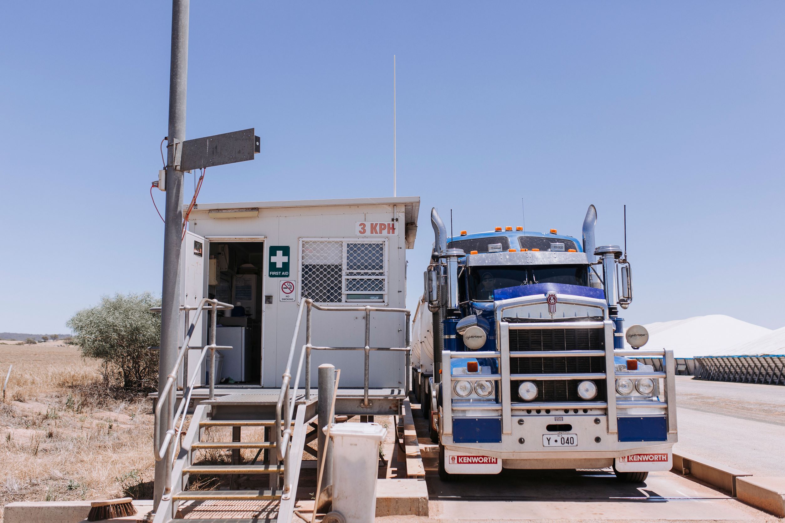 A blue truck is pulled up on the weighbridge alongside a sample hut at a CBH receival site