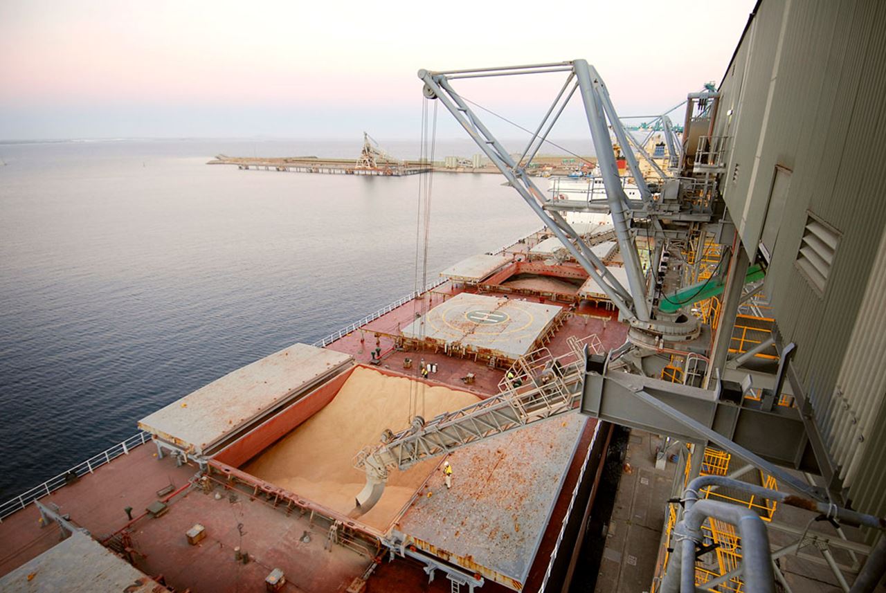 A ship is being loaded with grain at the Esperance Grain Terminal with a sunset in the background