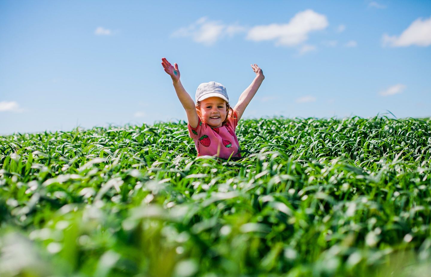 Child in field with hand up