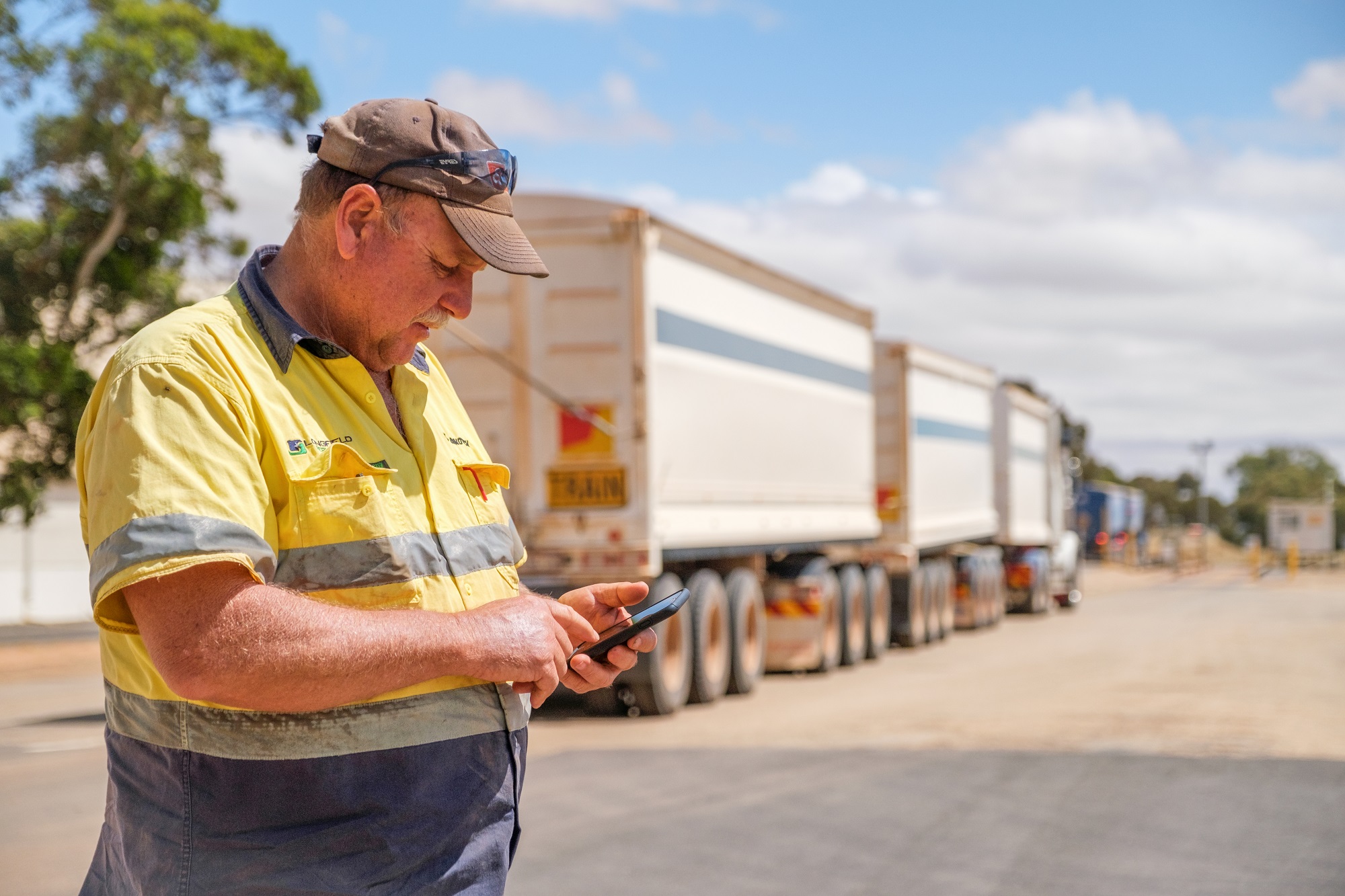 Man in hi vis looking at phone in front of truck